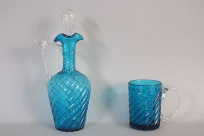 un pichet en verre bleu et un verre posés sur une table