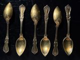 six spoons are lined up in a row on a black surface