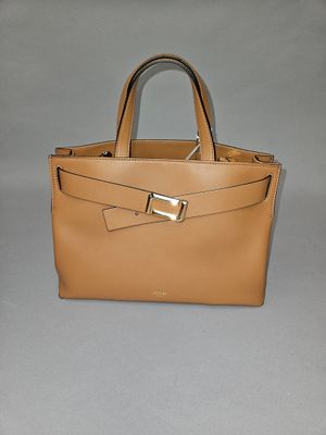 beige leather handbag with gold buckles on a grey background