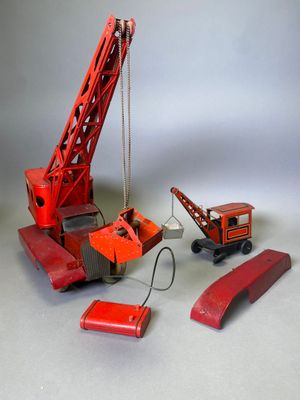 une petite grue rouge en plastique posée à côté d'un morceau de bois rouge