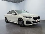 a white bmw m140i sedan parked in a showroom
