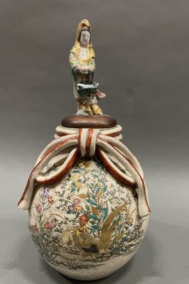 an image of a vase with a statue on top of it