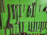 many tools hanging on a green wall in a room
