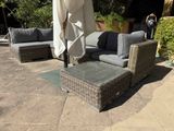 a couch and ottoman on a patio with an umbrella