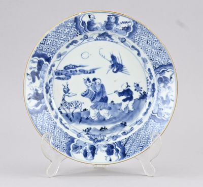 une assiette bleue et blanche ornée d'un motif représentant des personnages et des oiseaux