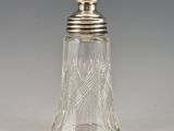 an antique cut glass salt shaker with a silver lid