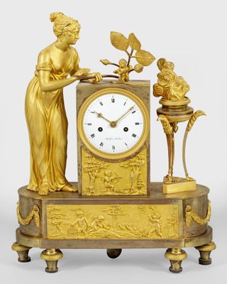 a gold clock with a statue on top of it