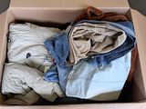 a cardboard box filled with clothes and a teddy bear