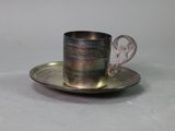 a silver cup and saucer sitting on a saucer