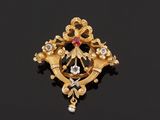 a gold and diamond broochle on a black surface