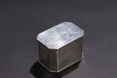 une petite boîte en argent posée sur une surface noire