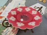 une assiette rose ornée de fleurs blanches, posée sur une table