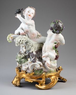 une figurine ancienne représentant deux chérubins, posée sur un socle en or