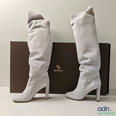 une paire de bottes blanches pour femme, avec une boîte posée sur un fond blanc