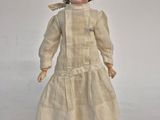 an old fashioned doll with a white dress and black shoes
