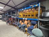 rows of chairs in a warehouse with shelves full of chairs