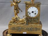 a gold clock sitting on top of a wooden stand