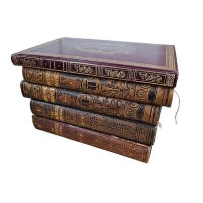 three old books stacked on top of each other on a white surface