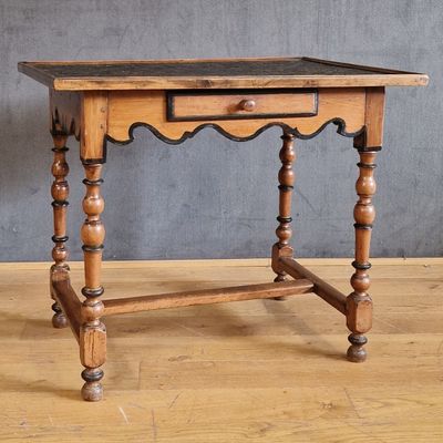 une vieille table en bois surmontée d'un tiroir, posée sur un parquet en bois massif