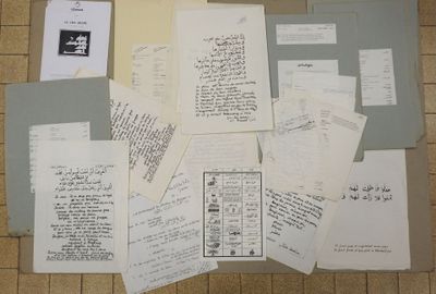 a pile of papers on the floor next to a laptop