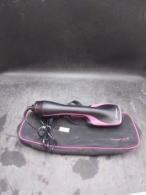 un sèche-cheveux noir et rose posé sur un sac noir