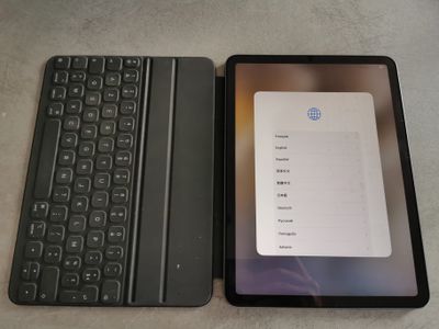 une tablette ouverte posée à côté d'un clavier sur une table