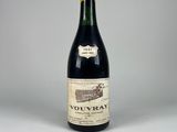 une vieille bouteille de vin posée sur une table blanche