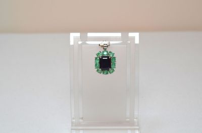 an image of a pair of emerald earrings on a clear display case