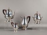trois théières en argent et une cafetière posées sur un support