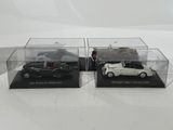 two black and white model cars in clear cases on a white surface