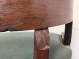 a close up of a wooden chair with a green seat