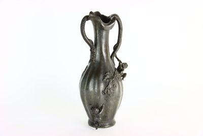 un vase en argent posé sur une surface blanche