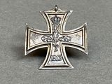 une vieille croix en argent surmontée d'une couronne, posée sur une table