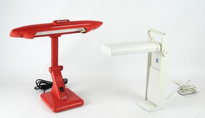 une lampe de bureau rouge qui se trouve à côté d'une lampe de bureau blanche