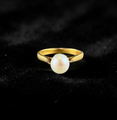 a gold ring with a white pearl on a black background