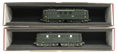 deux trains miniatures posés dans une boîte sur une surface blanche