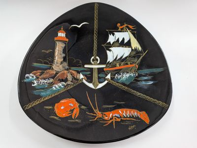 a black plate with a picture of a boat and a lighthouse