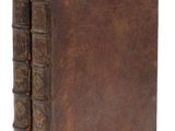 un vieux livre à la couverture brune posé sur une surface blanche