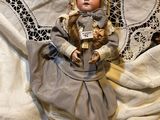 a doll that is laying on a bed with a white sheet