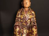 an old statue of a man sitting on top of a wooden floor