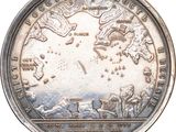 an old silver coin with a map of the world on it