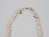 a close up of a necklace with pearls on a white surface