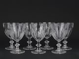 six verres à vin transparents alignés sur une surface noire