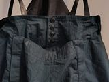 a black apron hanging on a wall with a pair of suspenders