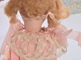 a doll that is wearing a pink dress and a pink hat