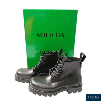 une paire de bottes noires posées à côté d'une boîte de Bottega