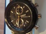 La montre est noire et possède un cadran doré.