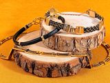 two bracelets with black and gold beads on a wooden stand