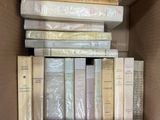 many books in a box that are stacked on top of each other