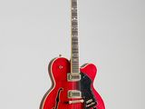 une guitare rouge accrochée à un mur sur fond blanc